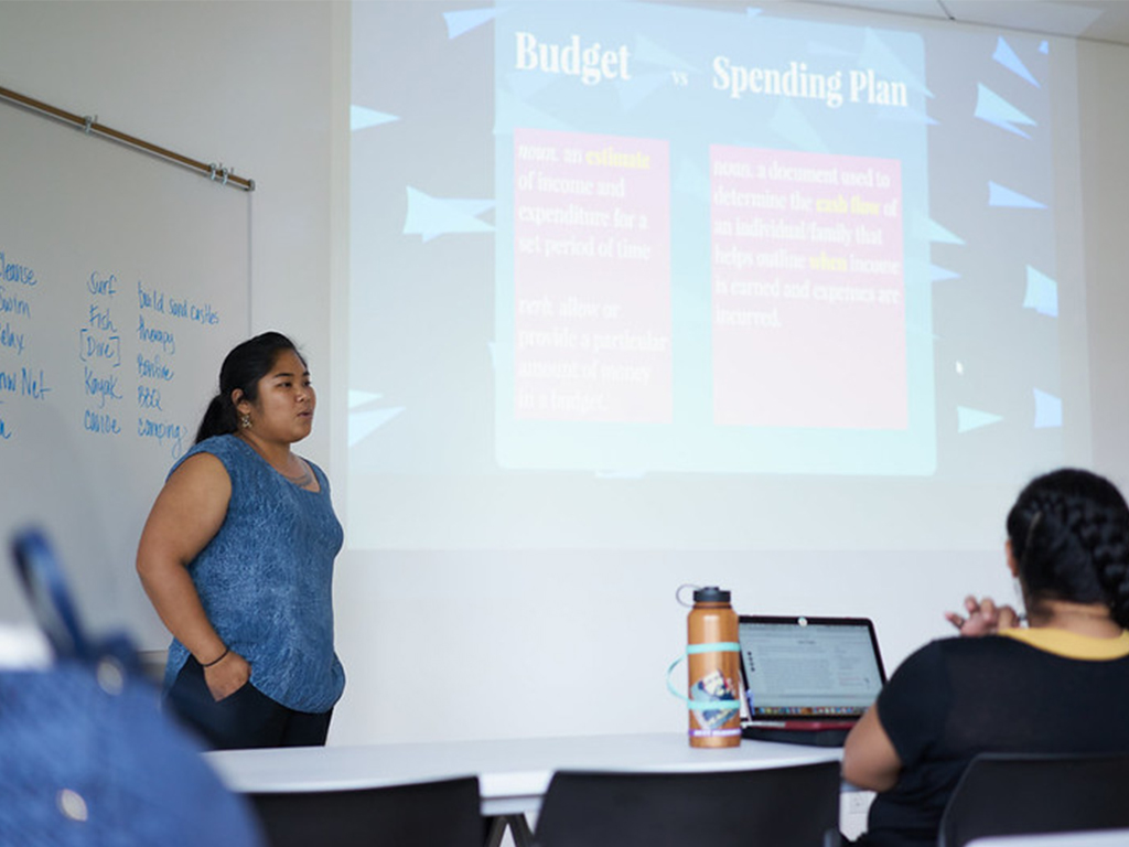 Saydee Pojas conducting a financial literacy presentation to attendees of an INPEACE Ho'olu Waiwai Program; Pojas was previously the program director of the family economic capacity building program