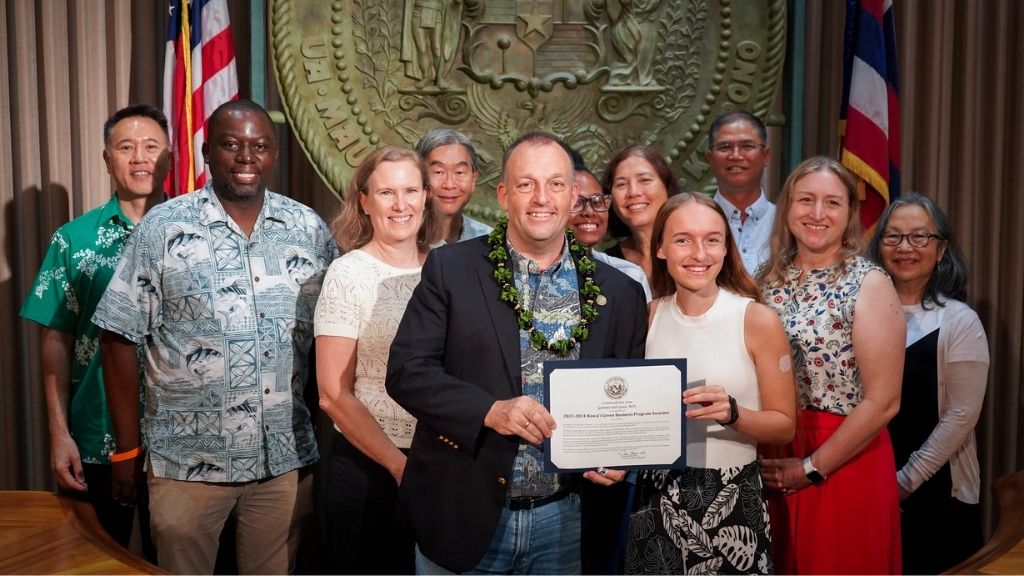 From left to right HPU representatives with State of Hawaiʻi Governor Josh Green and Hawaiʻi Green Business Program representatives: Clarence Ncube (HPU sustainability coordinator), Regina Ostergaard-Klem (co-instructor), Gov Green,Rasjell Foster (HON student just behind Gov Green), Linda Lierheimer (Residential Honors Program director), Camryn Potter (HON student holding certificate), and Barbara Quimby (co-instructor)