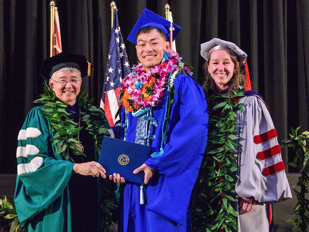 HPU President John Gotanda and Acting Senior Vice President and Provost Brenda Jensen with graduate Michael Matsushita