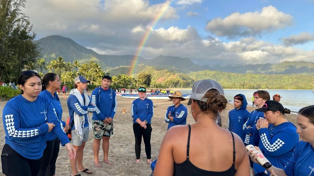 Paddlers from HPU's Nā Manō ʻo Ke Kai and I Mua One Blade gather on the coast of Hanalei Bay before embarking on the Na Pali Challenge, a 37-mile journey along Kauaiʻs famous Nā Pali Coast that attracts top paddlers from around the world