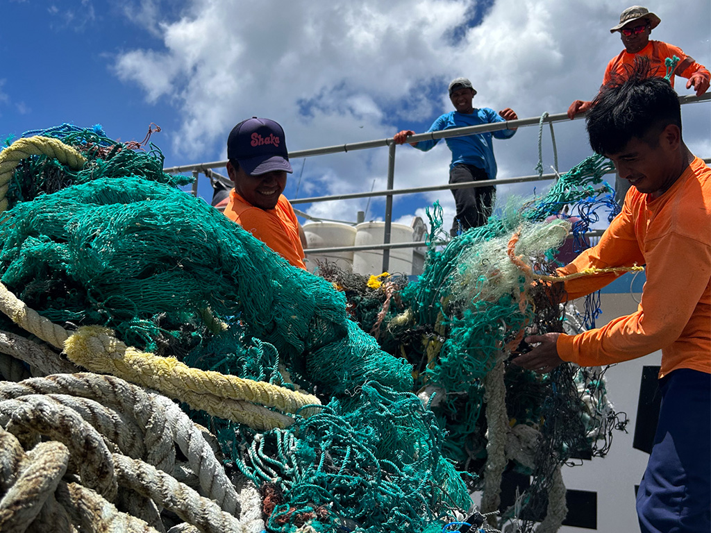Two researchers detangle a large pile of derelict fishing gear at the original net shed.